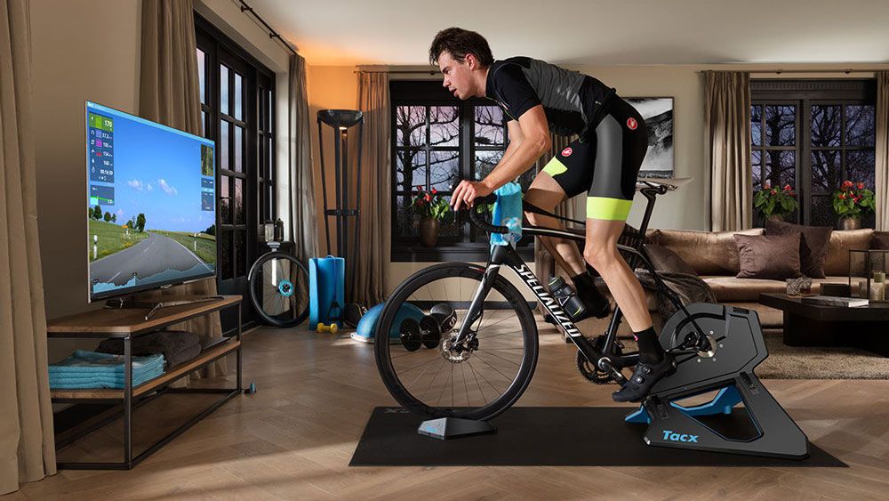 Man riding a Specialized road bike attached to a Tacx Neo 2T turbo trainer in front of a flat screen TV