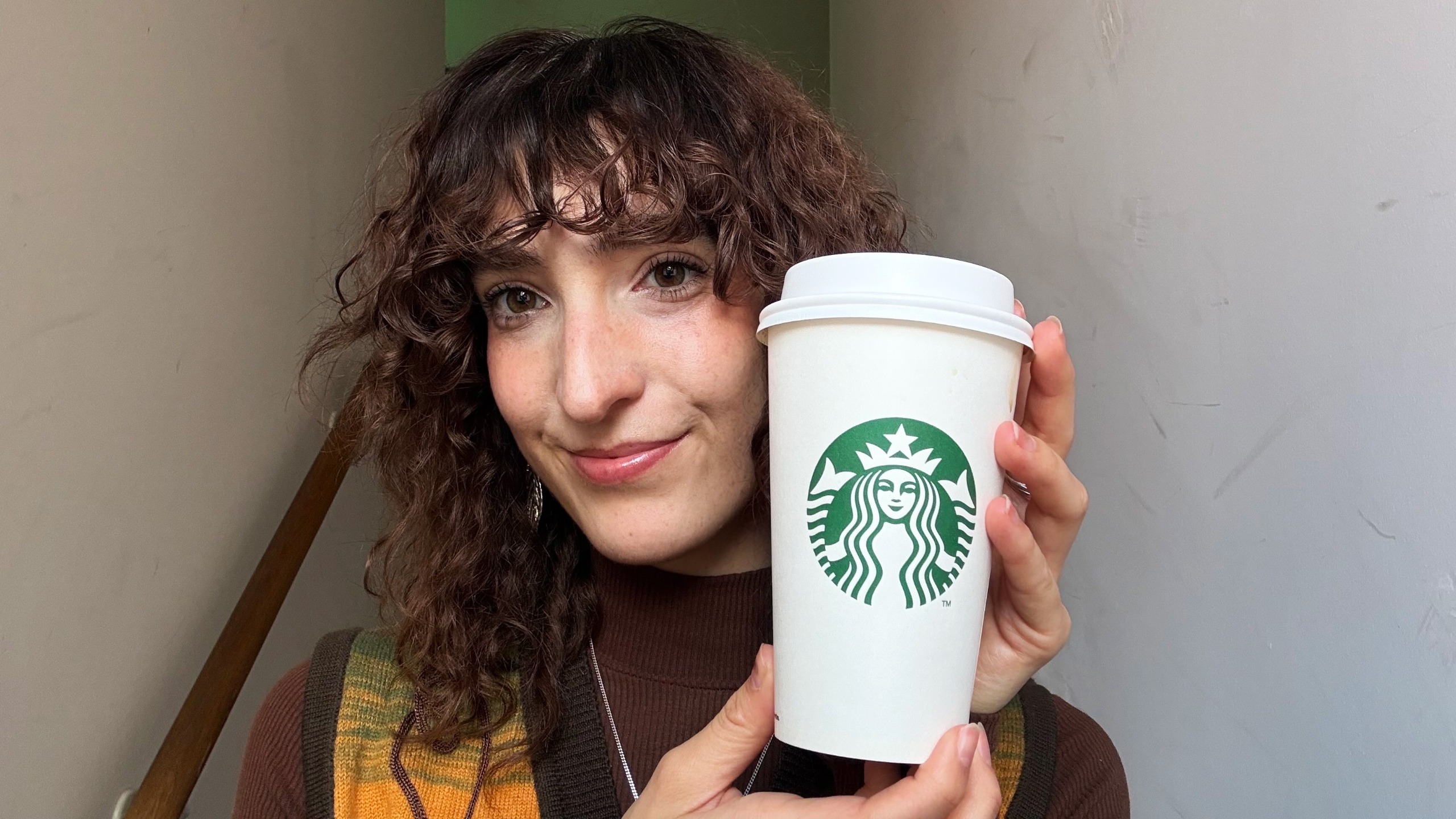 the author holding a starbucks pumpkin spice latte