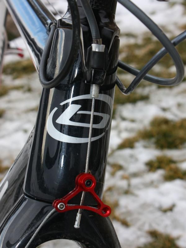 Page bypasses the stock noodle on the steerer-mounted housing stop for a smoother cable path and uses just one set screw to lock in the centering adjustment.