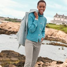 Woman wearing blue knitted cardigan and grey jeans with coast background