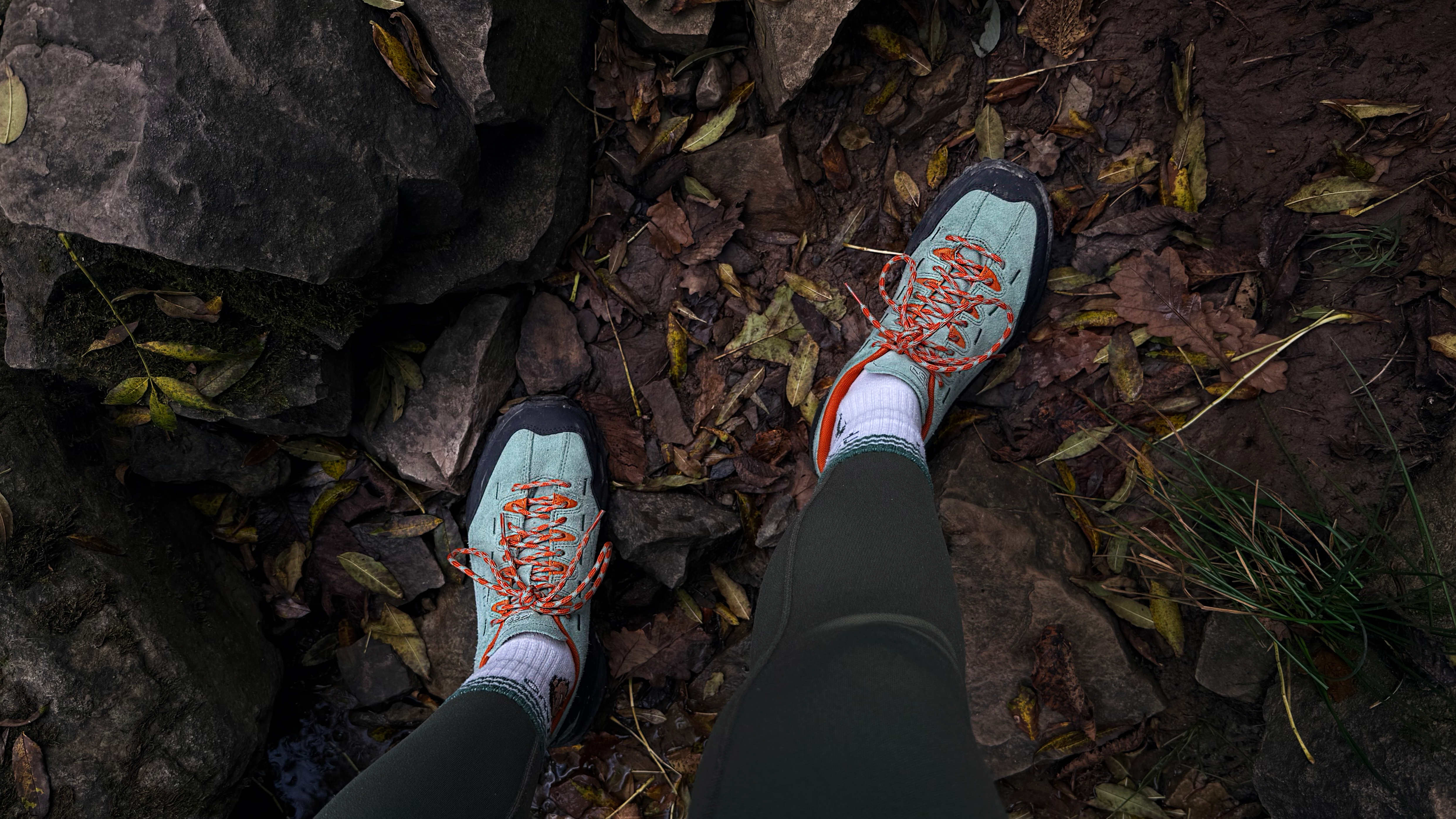 the keen jasper zionic hiking shoes in green/gold colorway photographed with rocks and leaves on a hiking trail