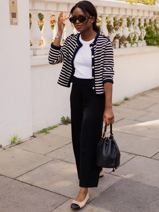 a photo of a woman wearing a striped cardigan with a T-shirt, black trousers, ballet flats
