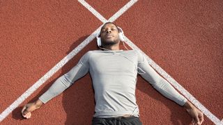 Man lying on running track wearing headphones