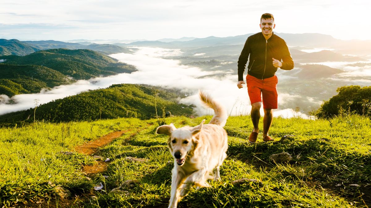 A man running up a mountain with his dog