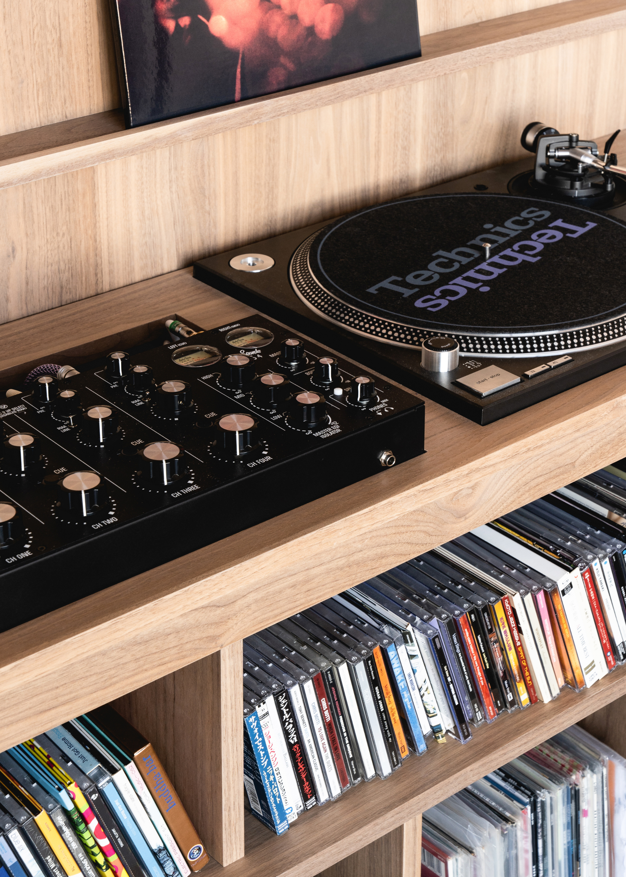 A close-up of a wooden cabinet with a turntable and a collection of CDs and vinyl