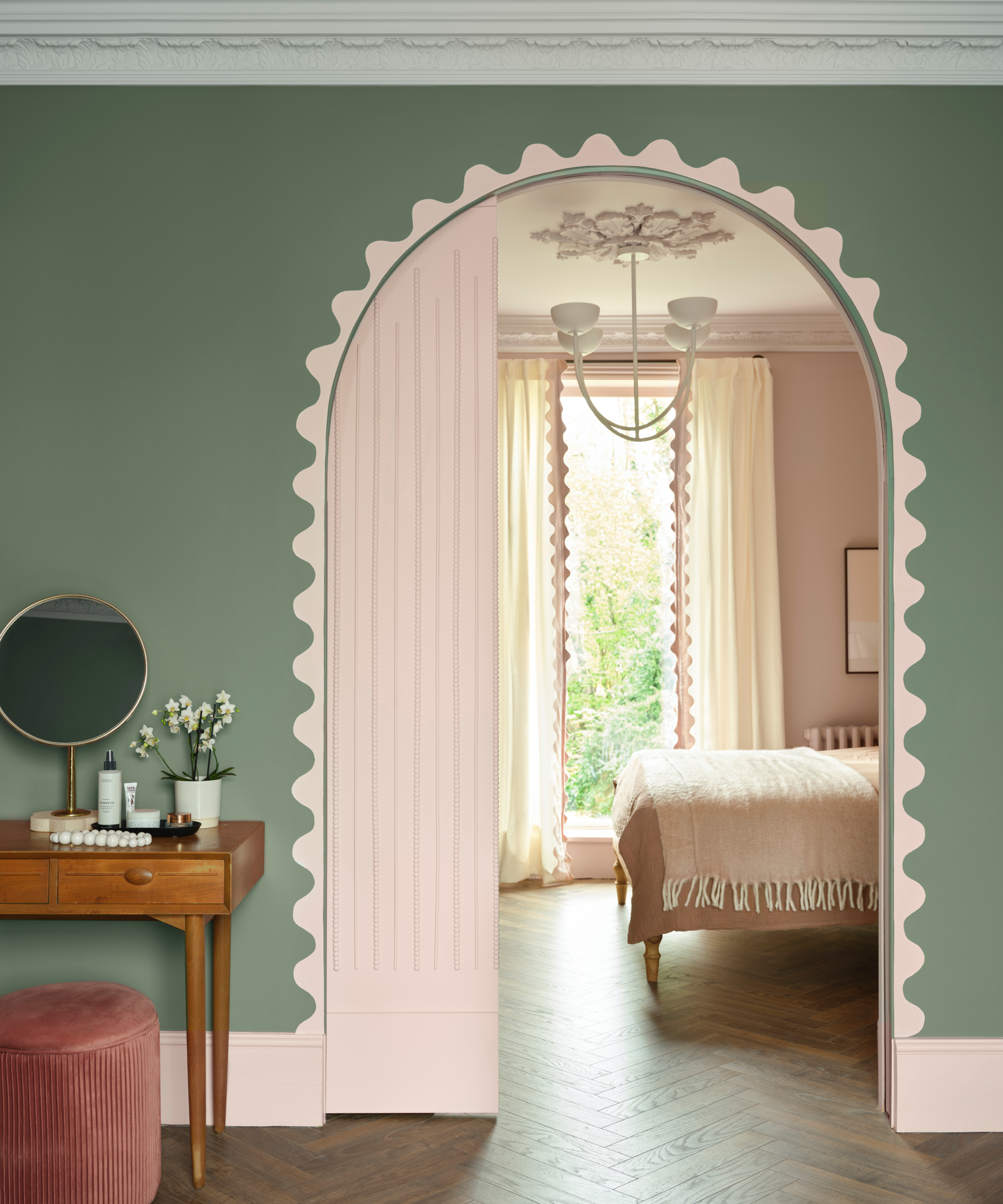 bedroom and dressing room with green walls, pink skirting, arched door with pink scallop design painted around edge of door