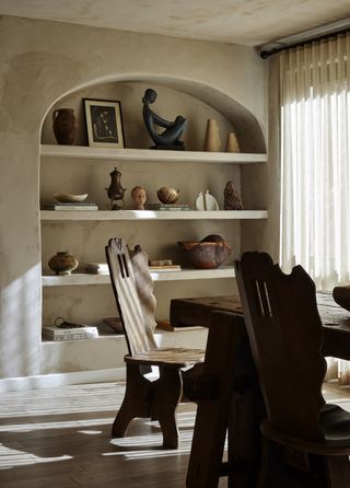 dining room with antique dining chairs and open shelving filled with ceramics, sculptures and books