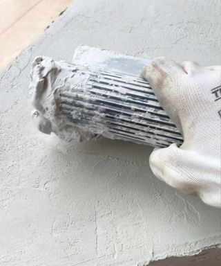 Spreading plaster on the Cardboard DIY coffee table with a trowel. I'm wearing white gloves