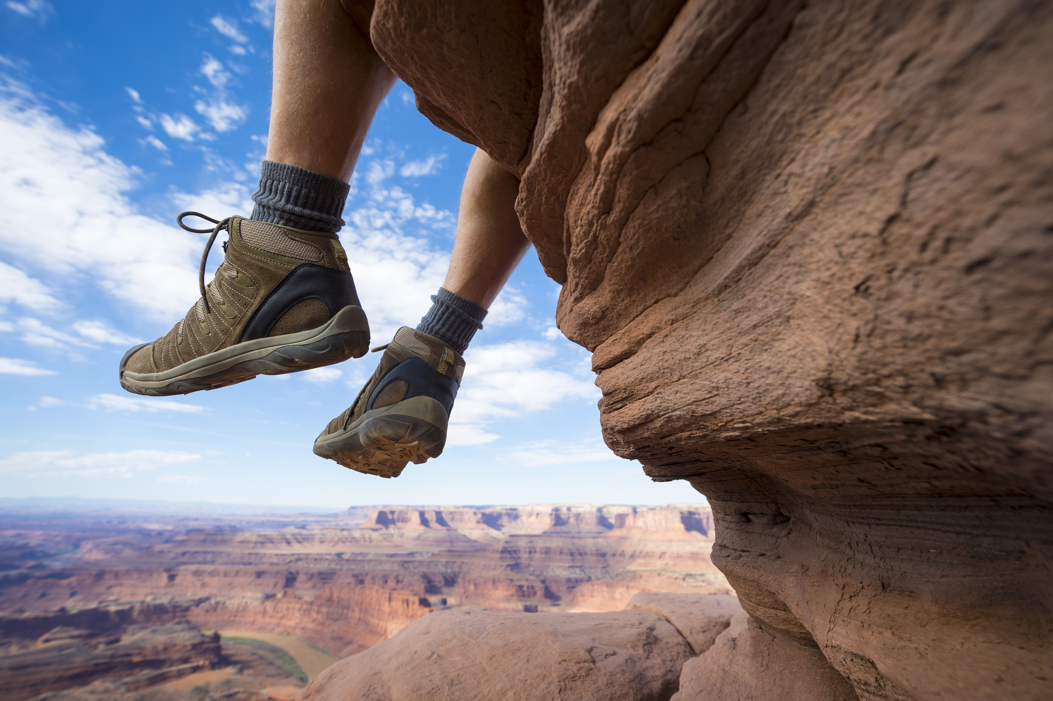 Portrait of the boots of a hiker hanging outdoors above dramatic canyon landscape.