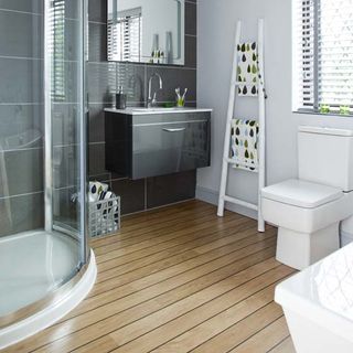 bathroom with wooden flooring and grey tiled wall