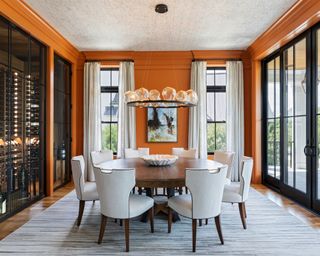 dining room with bright orange walls, traditional furniture and large glass doors