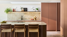 modern kitchen with dusty pink handless cabinets and a wooden curved kitchen island