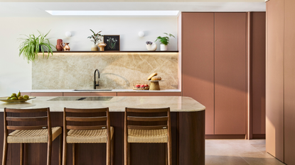 modern kitchen with dusty pink handless cabinets and a wooden curved kitchen island
