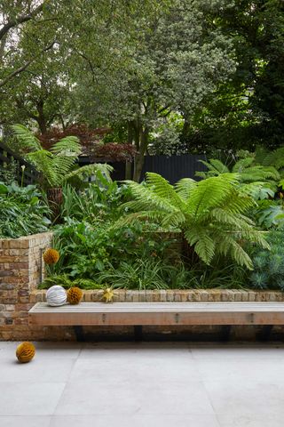 modern porcelain paving with greenery behind and bench