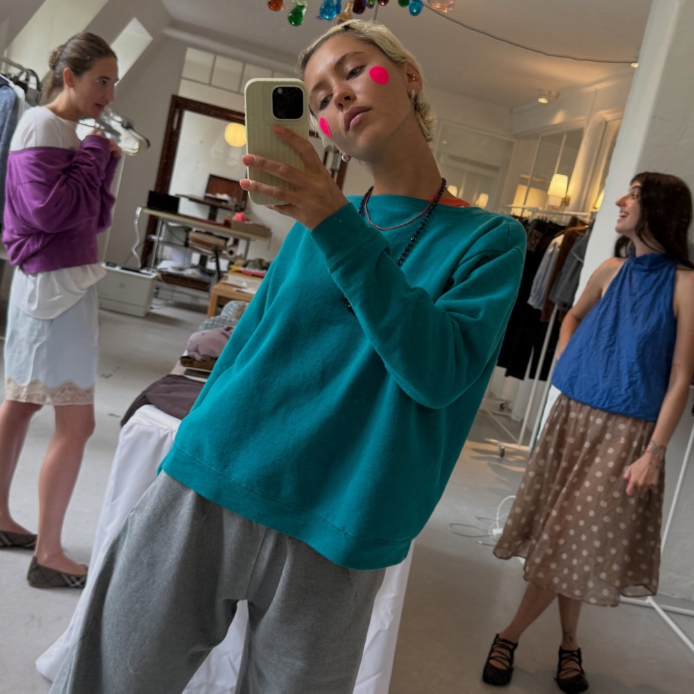 Iris Law takes a mirror selfie wearing grey lace-trim trousers with ballet flat mary janes and a teal knit.