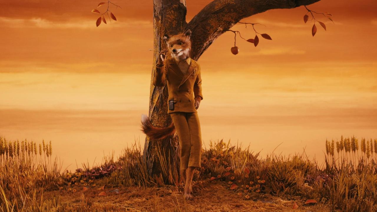 fantastic mr fox wearing a brown suit as he leans against a tree with an orange backdrop in a stop motion still from the wes anderson movie