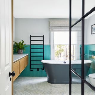 A bathroom with a freestanding bath and turquoise wall