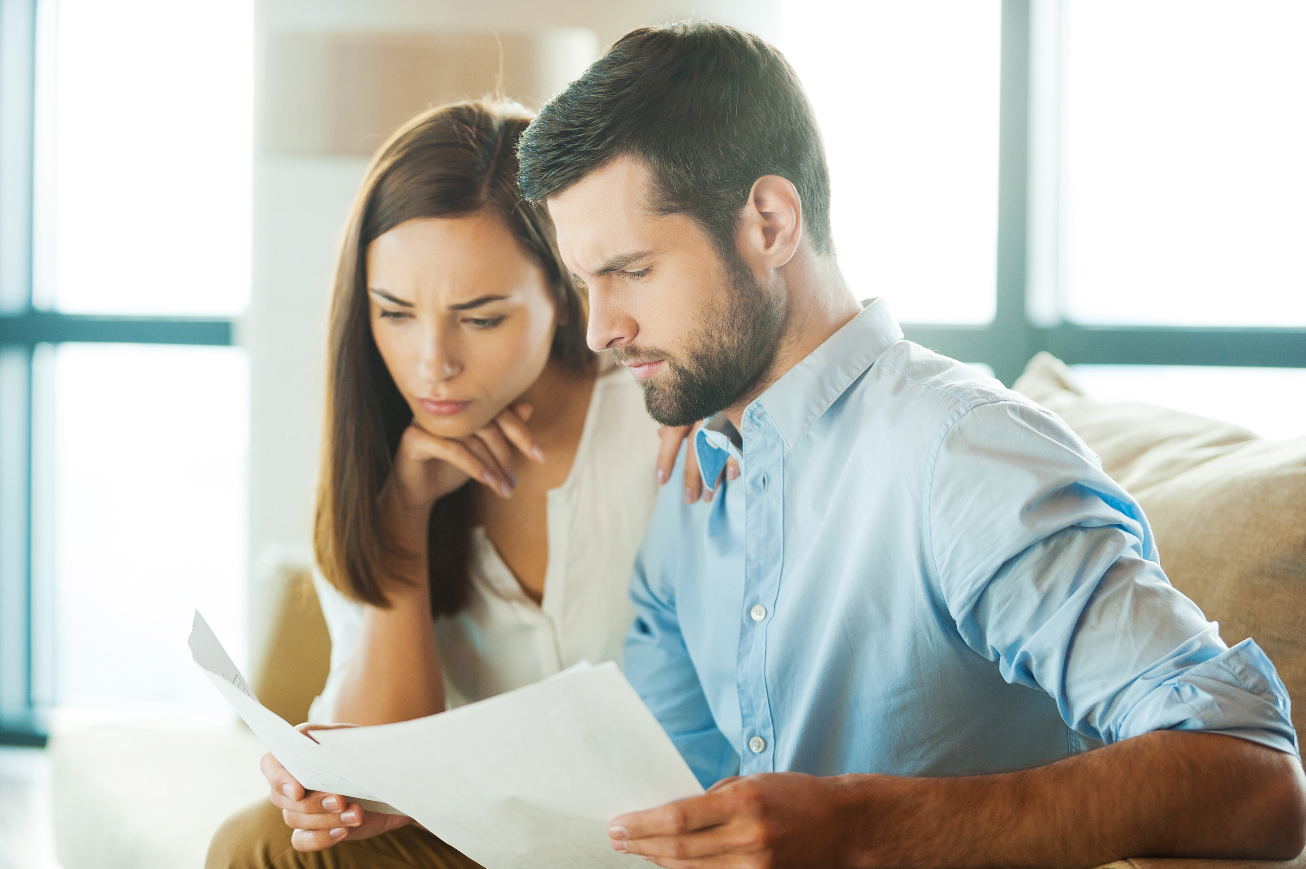 Young couple look seriously at documents, symbolising they are writing a will.