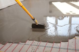Wet self levelling being spread over a loose wiring electric underfloor heating system