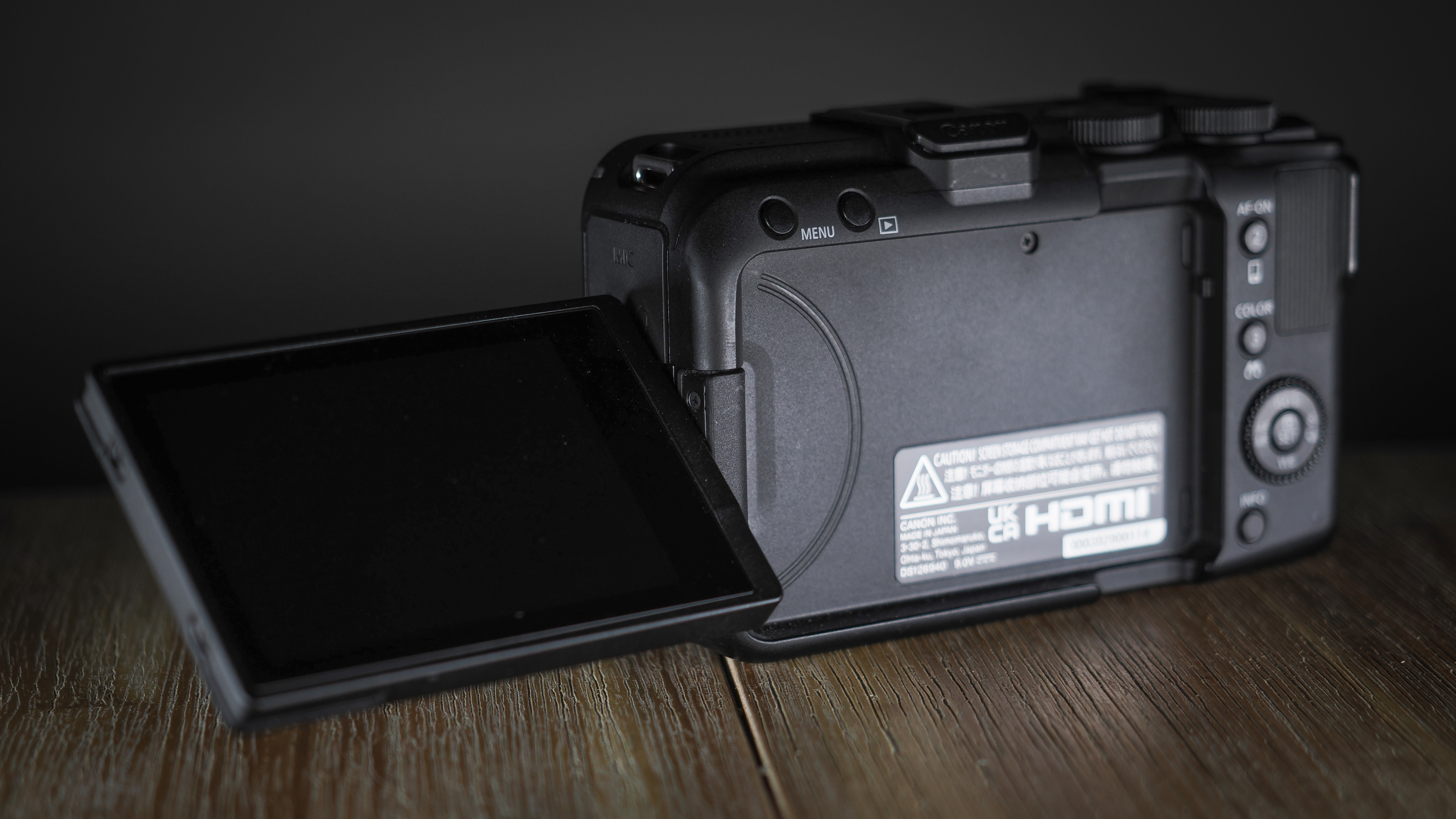 Canon EOS R50 V on a wooden surface, against a dark background