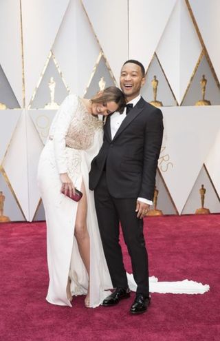 Chrissy Teigen and John Legend posing together on Oscars red carpet