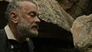 Tom Hanks stands underneath some rocks to hide from a gunman in News of the World