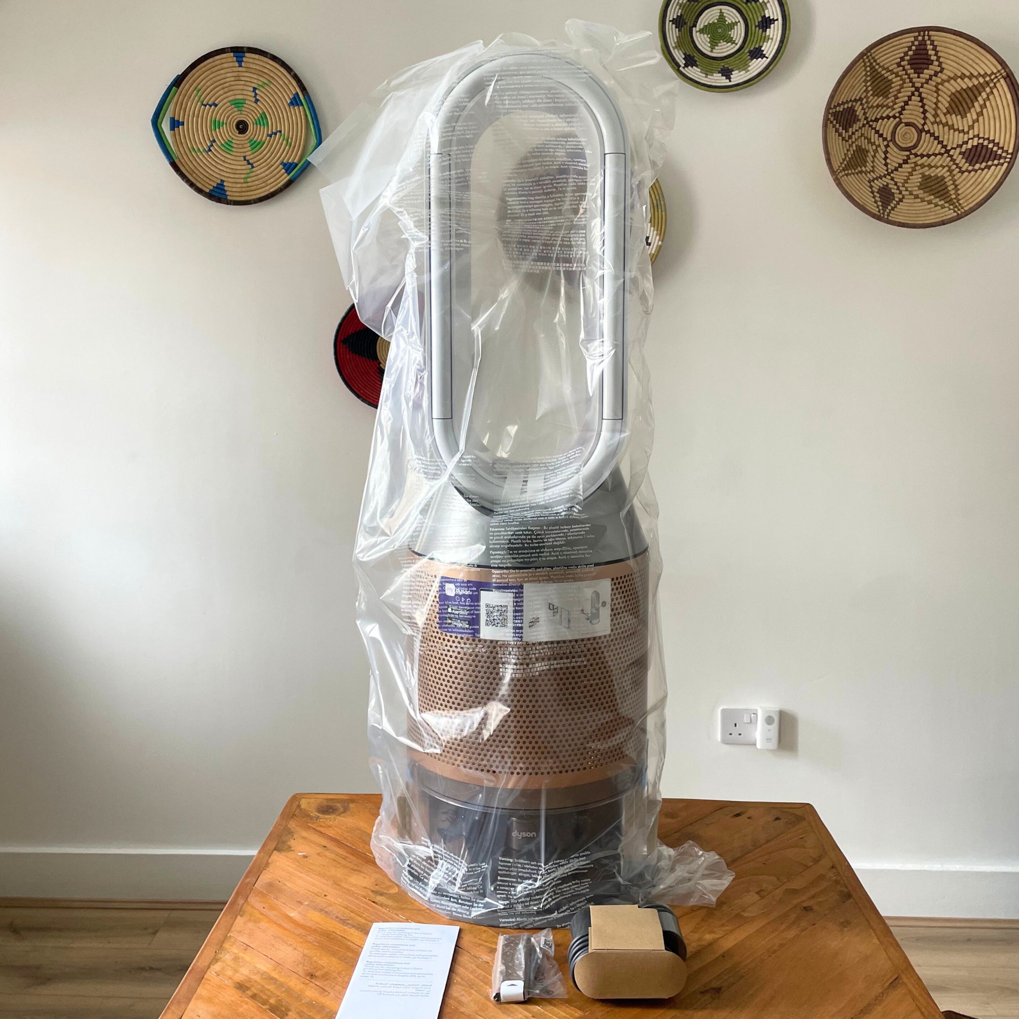 Dyson Purifier Humidify+Cool PH2 De-Nox wrapped in plastic packaging, sitting on a wooden table