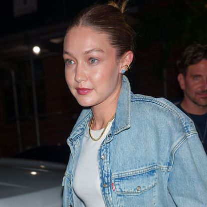 Gigi Hadid wearing a denim jacket, metallic track pants, and mesh flats