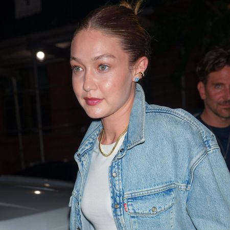 Gigi Hadid wearing a denim jacket, metallic track pants, and mesh flats