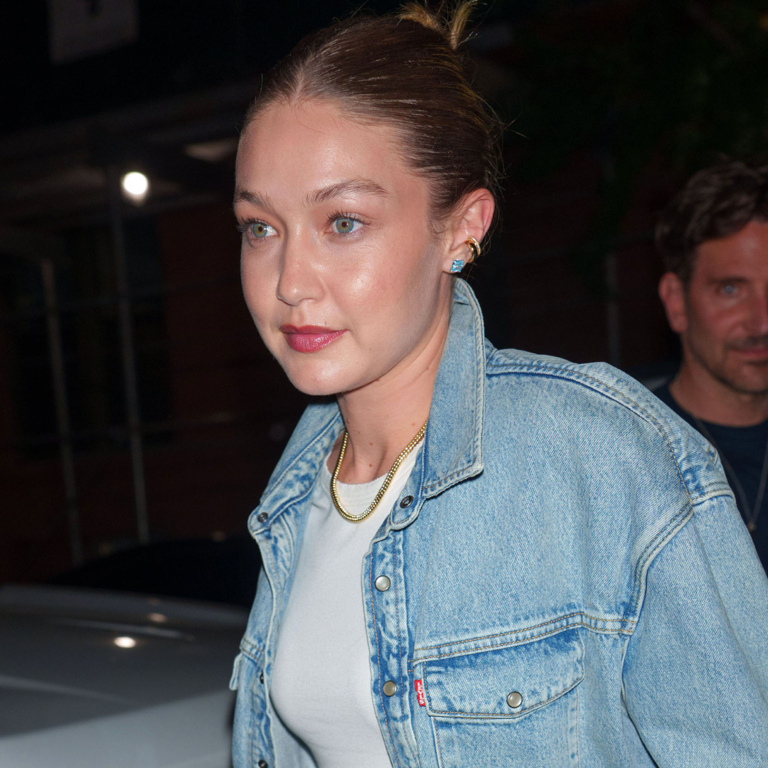 Gigi Hadid wearing a denim jacket, metallic track pants, and mesh flats