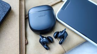 Bose QuietComfort Earbuds 2 ligger ved siden av etuiet og en telefon