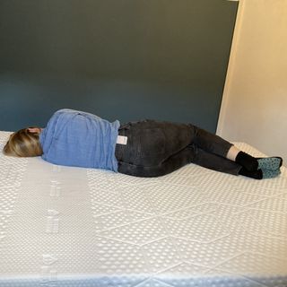 Woman lying on a white mattress in a white and blue walled room