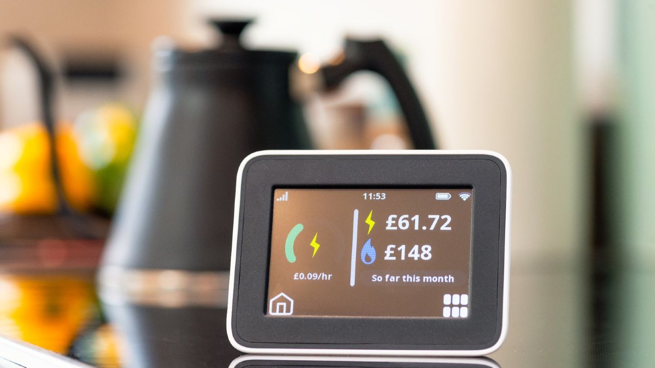 Close-up of the screen of a smart meter display in a kitchen, showing the monthly cost of electricity and gas so far.