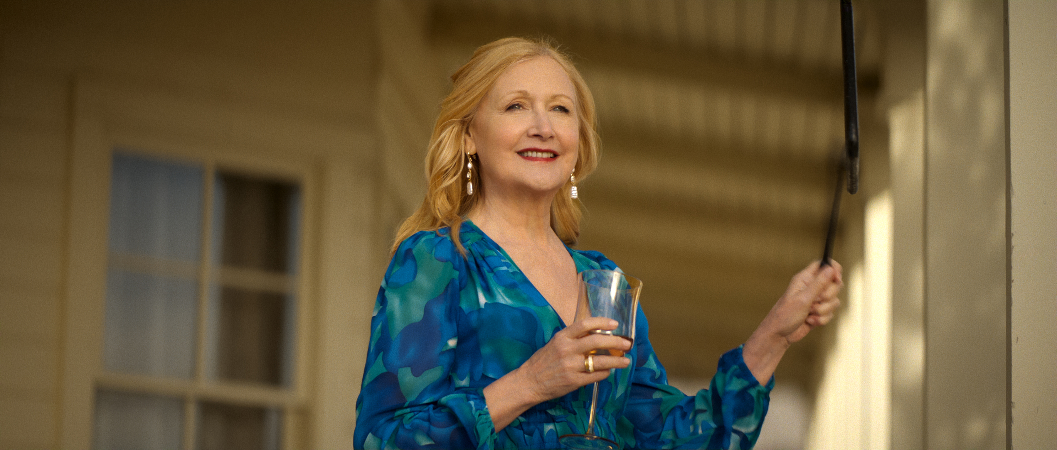Patricia Clarkson as Claire O&amp;rsquo;Grady, holding a champagne glass and standing on a porch, in Episode 204 of Netflix's 'Ransom Canyon' Season 2.