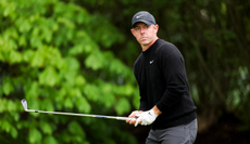 Rory McIlroy holds an iron and lines up his shot