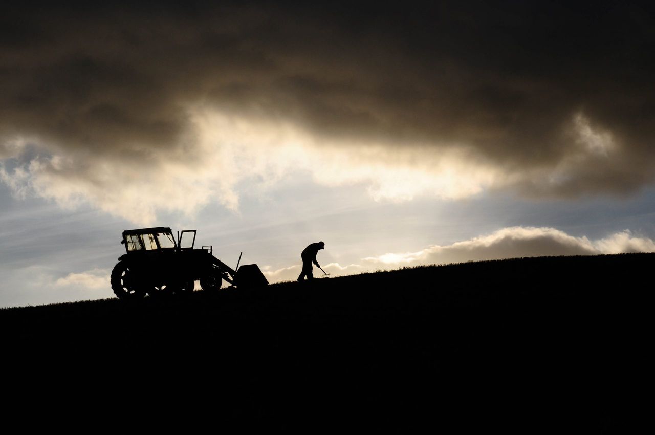 Silhouette of farmer working and tractor