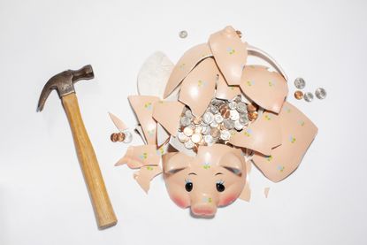 Callable CD concept: Smashed piggy bank containing US coins with hammer on white surface, view from above. 