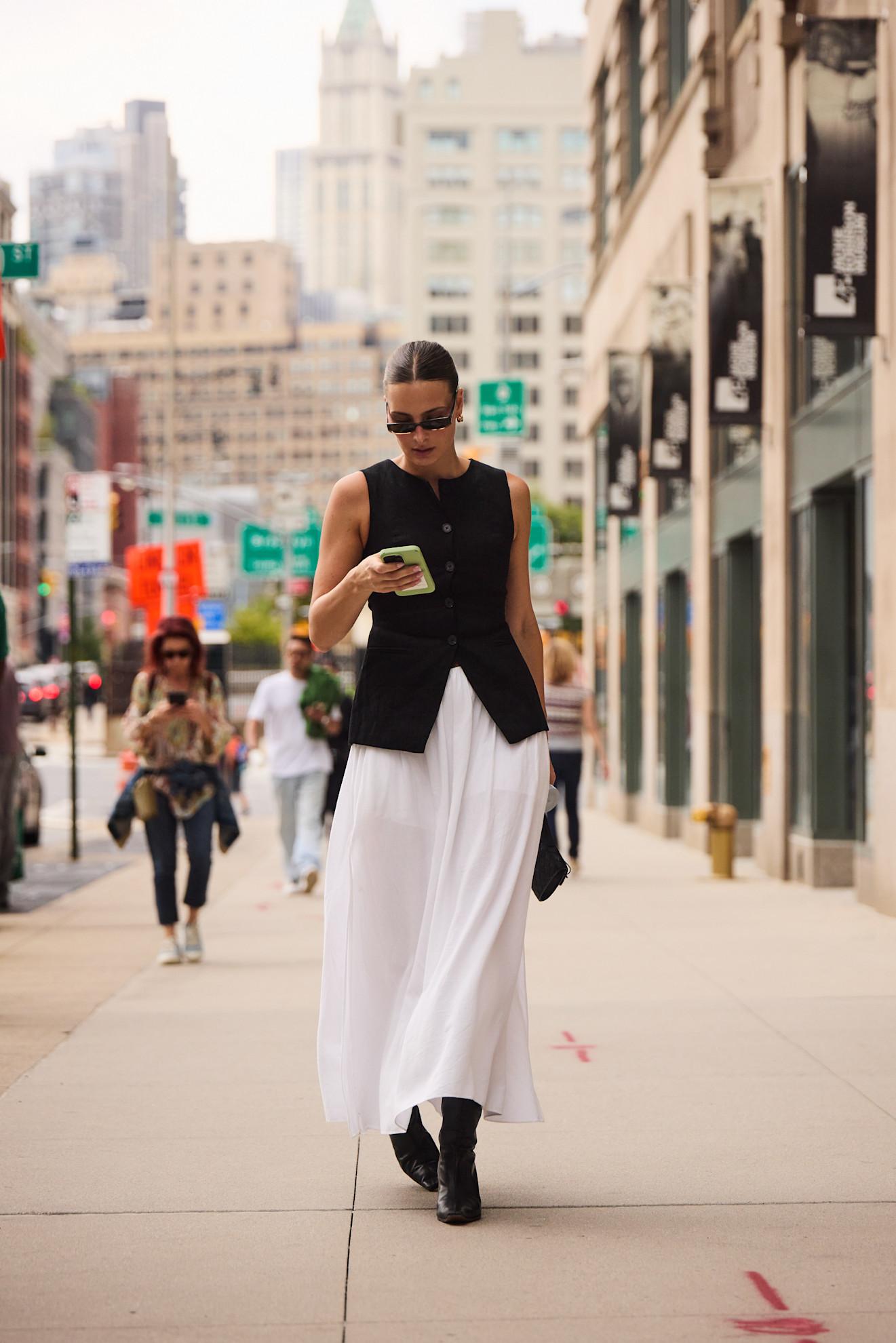 woman wearing a black vest, white skirt, and black boots in New York