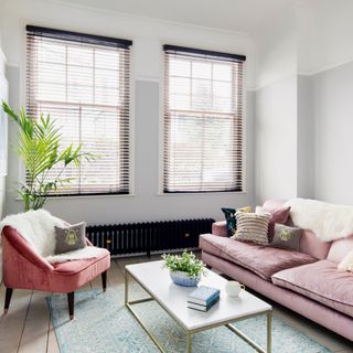 Grey living room with pink sofa and pink armchair and blinds on windows