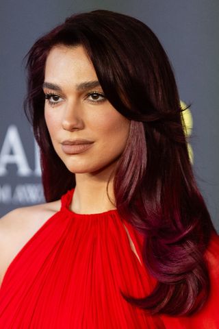 Dua Lipa is pictured with burgundy brown hair whilst attending the 2024 EE BAFTA Film Awards at The Royal Festival Hall on February 18, 2024 in London, England.