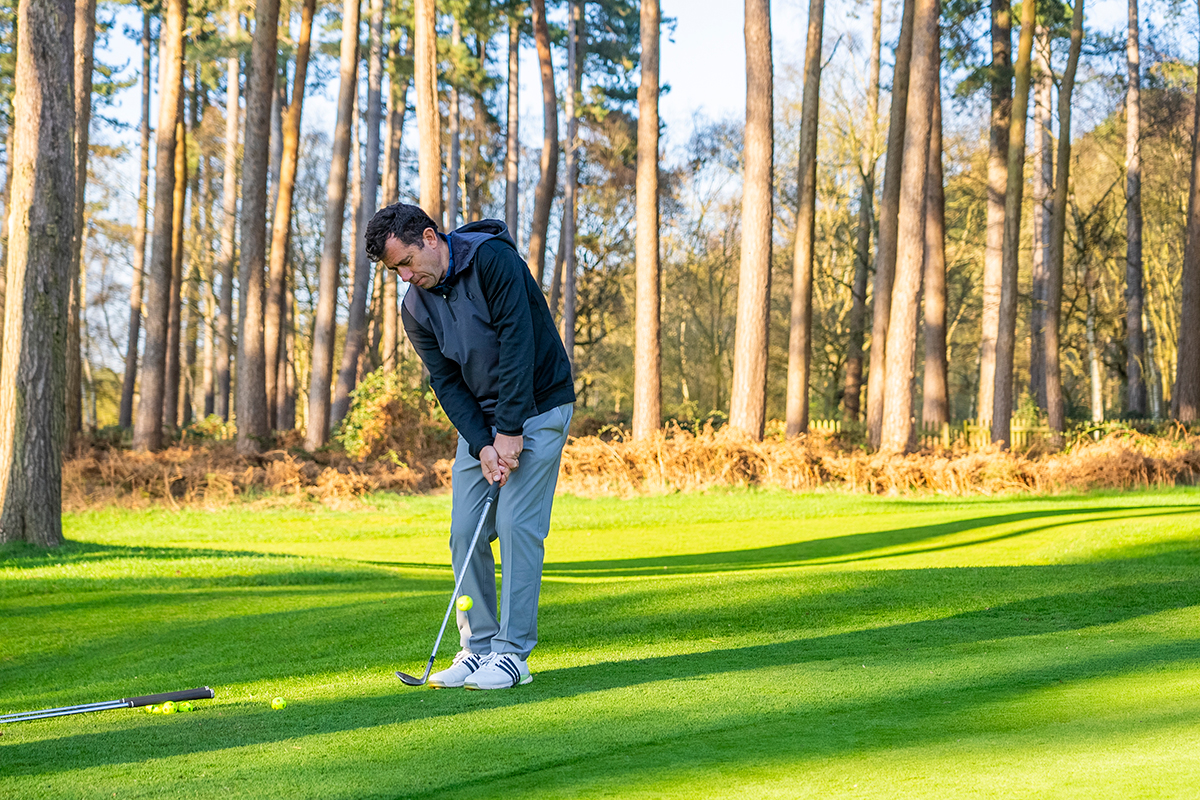 Dan Grieve hitting a chip shot with a wedge from just off the green at Woburn Golf Club