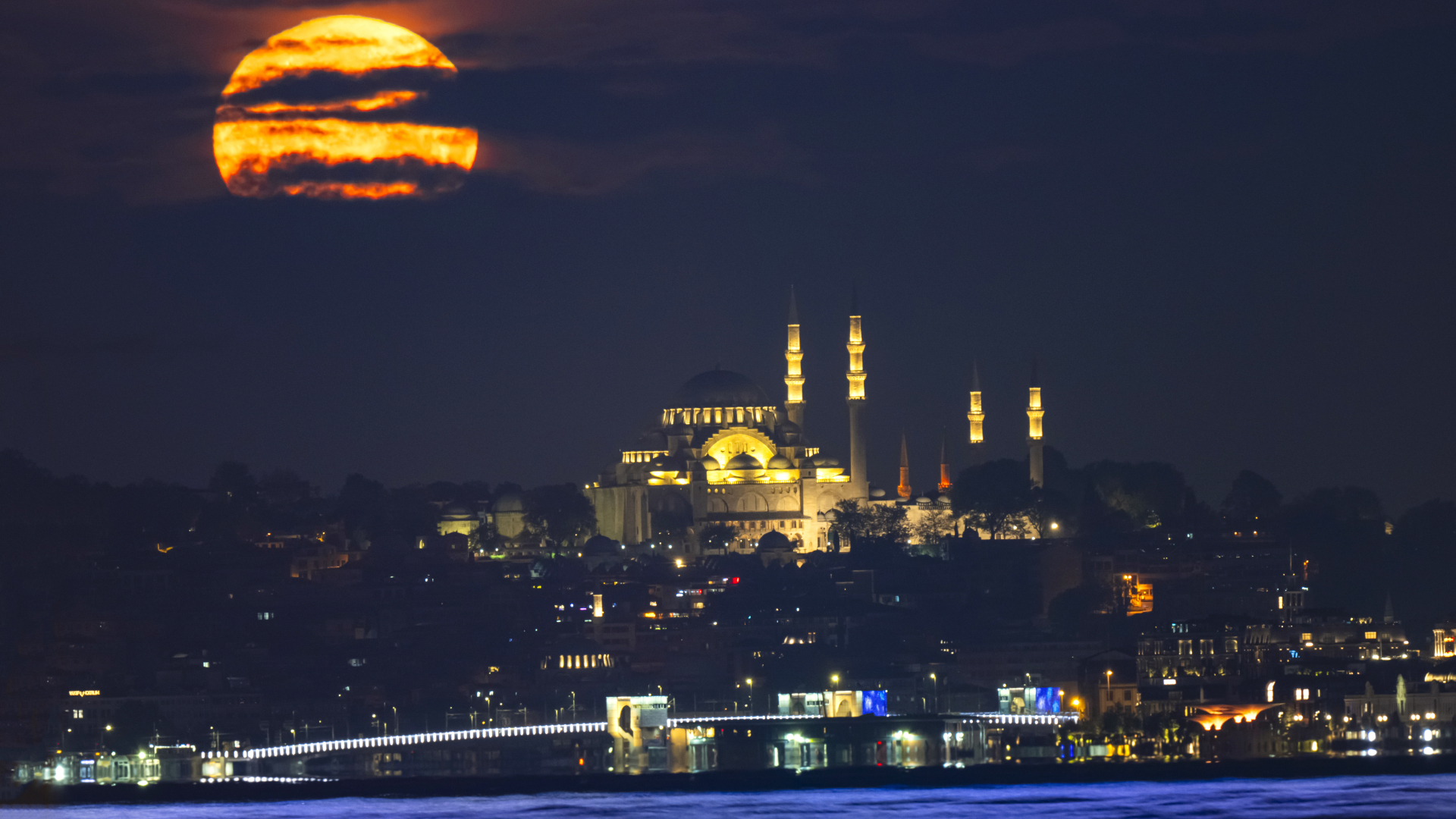 The Yellow hued Flower Moon can be seen shining above the Suleymaniye Mosque in Istanbul, Tuykey on the night of May 12. It is partially covered in streaks of cloud, while the mosque and city are lit with artificial light.