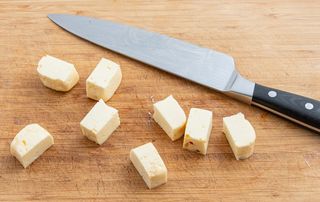 Raw cubes of halloumi next to a knife