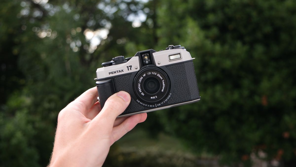 A Pentax 17 film camera held in a hand outside