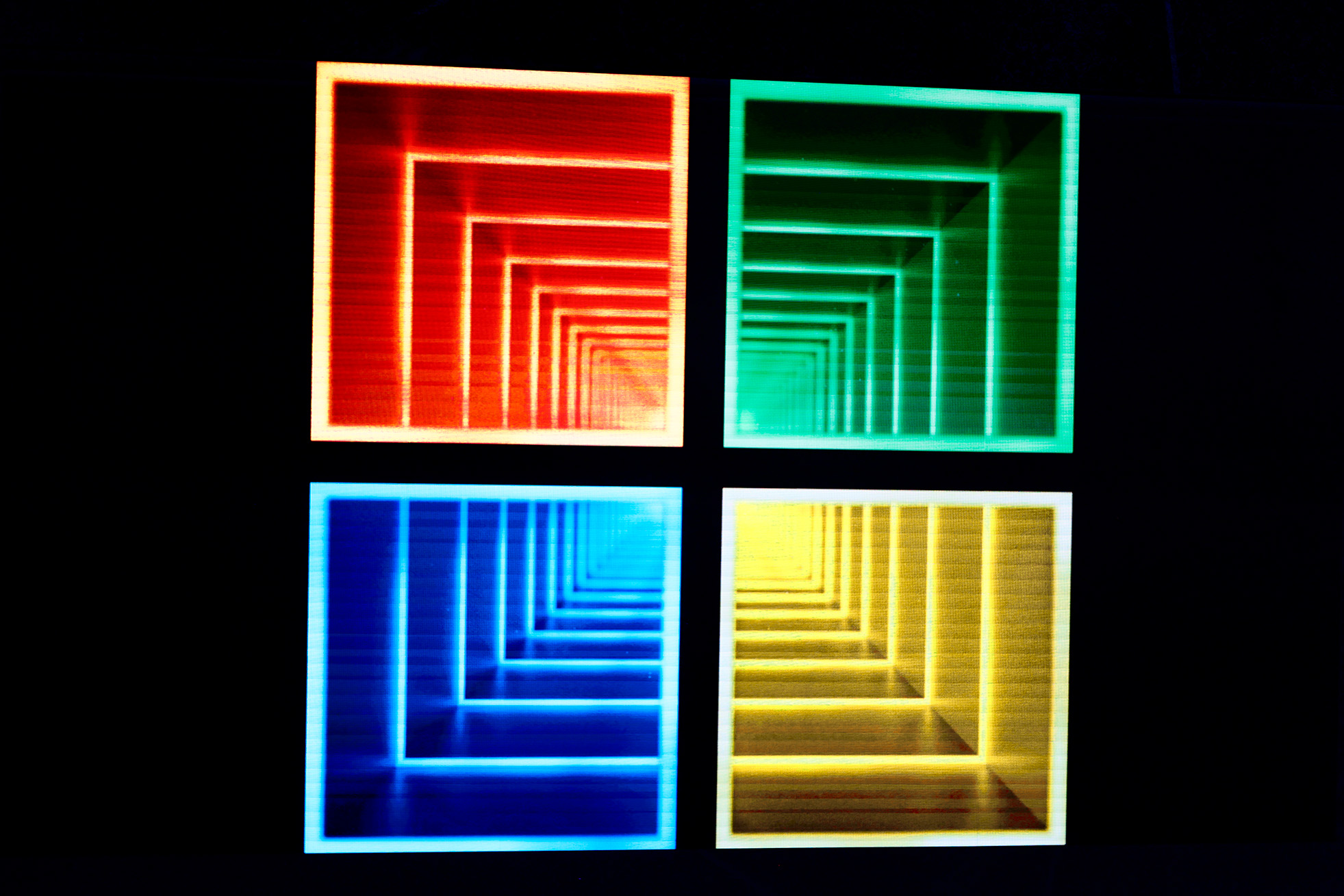 A digital representation of the Microsoft logo, containing endless boxes of color within each of the four colored sqaures that make up the logo against a dark background, to form a 'tunnel' effect