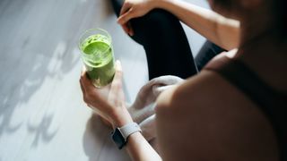 Woman holding cup of green juice post-workout, experiencing the benefits of magnesium