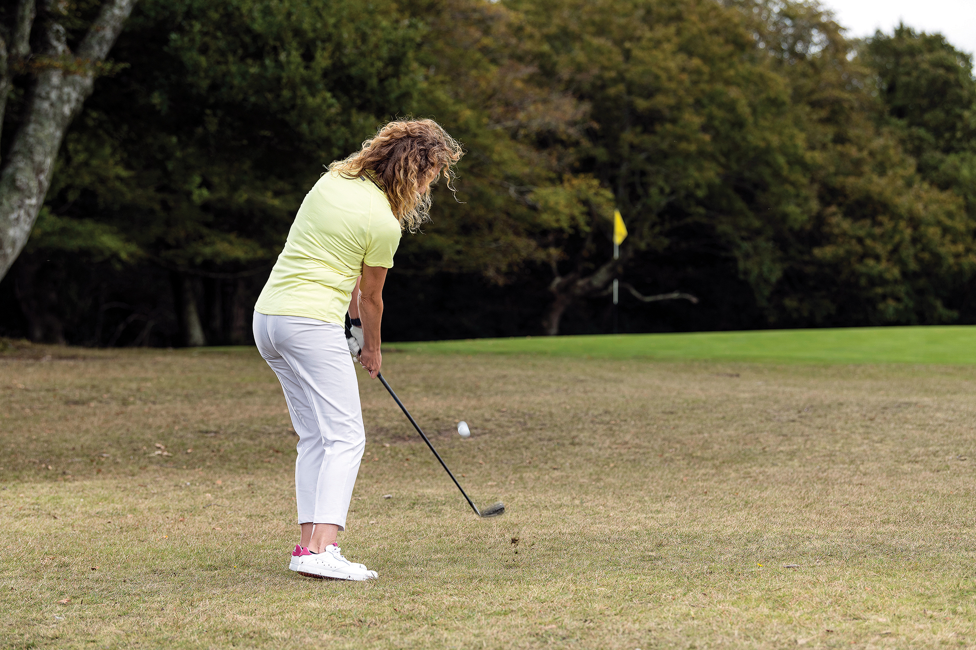 Katie Dawkins hitting a low 'giant' chip and run to keep the ball low under a tree branch and letting it scamper up onto the green