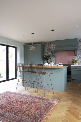 Green shaker kitchen with centre breakfast bar and brass bar stools