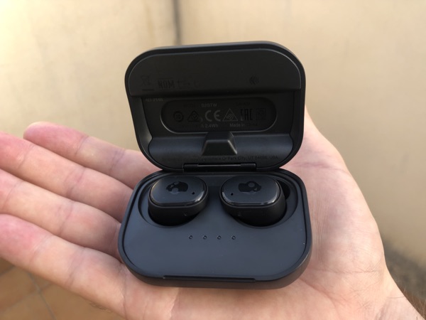 Ett par Skullcandy Grind True Wireless Earbuds som ligger i sitt laddningsfodral i en öppen handflata.