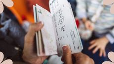 A woman holding plane tickets in an airport, used to illustrate an article on how to get the best flight deals